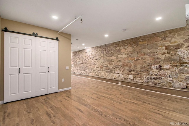 unfurnished room with recessed lighting, a barn door, and wood finished floors