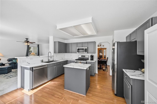 10530 Mount Columbia Pl, Parker, CO 80138 - kitchen with stainless steel appliances, gray cabinetry, a center island, open floor plan, and light wood-style floors