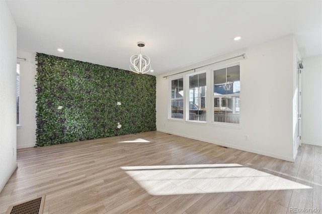 unfurnished dining area with light wood-type flooring, a notable chandelier, and a wealth of natural light