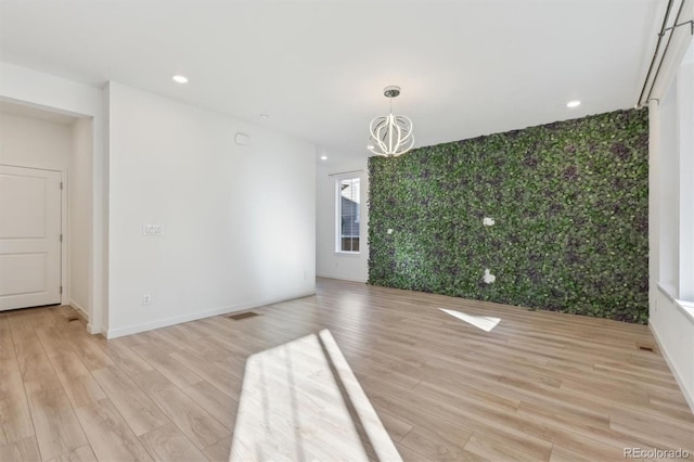 unfurnished living room with light hardwood / wood-style floors and a chandelier