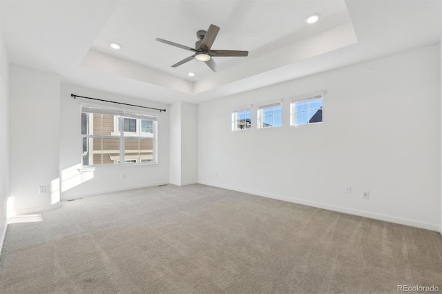 empty room featuring ceiling fan, a tray ceiling, and light colored carpet