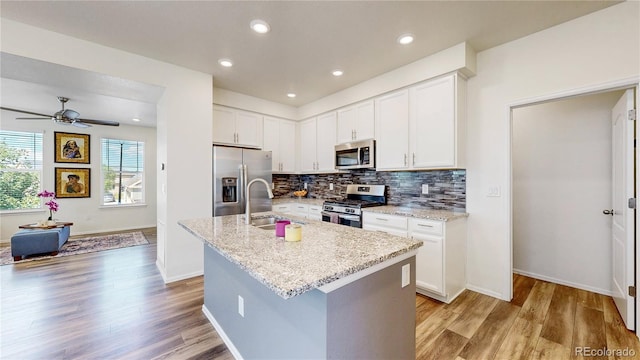 14074 Jackson St, Thornton, CO 80602 - kitchen featuring stainless steel appliances, light wood-style flooring, tasteful backsplash, light stone countertops, and recessed lighting