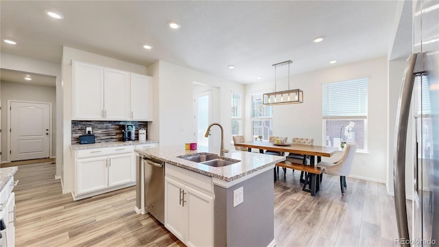 14074 Jackson St, Thornton, CO 80602 - kitchen featuring stainless steel appliances, decorative backsplash, white cabinets, light stone countertops, and light wood-type flooring