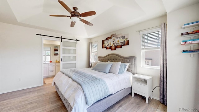 14074 Jackson St, Thornton, CO 80602 - bedroom featuring a raised ceiling, light wood-style flooring, a barn door, and ensuite bath
