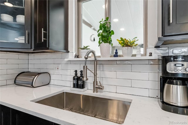 10550 Routt St, Westminster, CO 80021 - kitchen featuring backsplash, light stone countertops, glass insert cabinets, and a sink