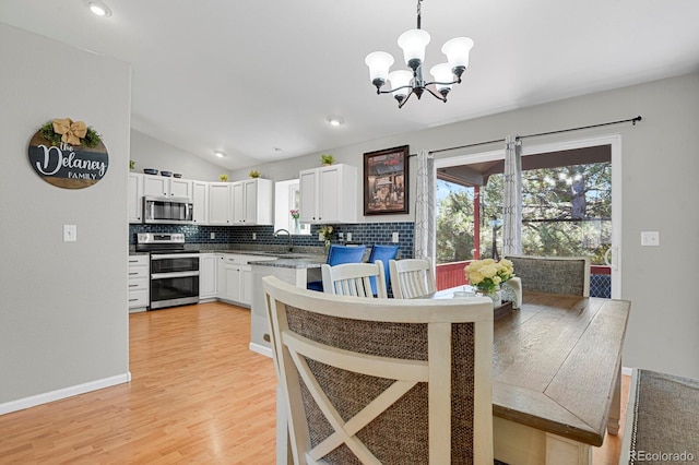 dining area featuring a chandelier, lofted ceiling, light wood finished floors, recessed lighting, and baseboards