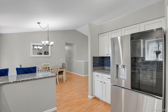 kitchen with stainless steel fridge, white cabinets, lofted ceiling, backsplash, and light wood finished floors