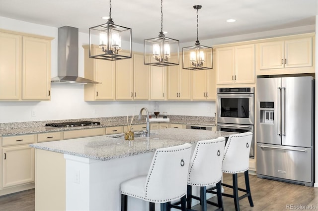 6692 S Robertsdale Way, Aurora, CO 80016 - kitchen with stainless steel appliances, wall chimney exhaust hood, cream cabinets, a chandelier, and recessed lighting