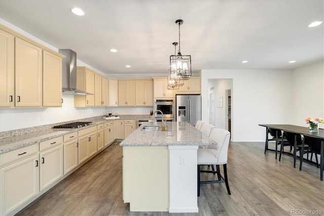 6692 S Robertsdale Way, Aurora, CO 80016 - kitchen with wall chimney exhaust hood, stainless steel appliances, wood finished floors, recessed lighting, and a breakfast bar