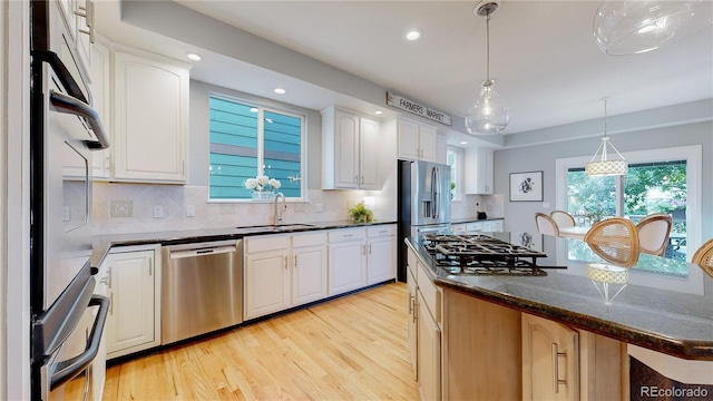 kitchen featuring pendant lighting, white cabinetry, sink, a center island, and stainless steel appliances