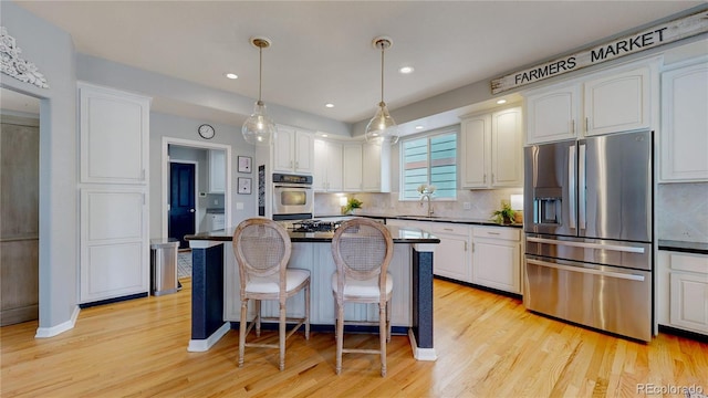 kitchen with white cabinetry, sink, stainless steel appliances, and a kitchen breakfast bar