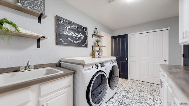 laundry area featuring cabinets, separate washer and dryer, and sink