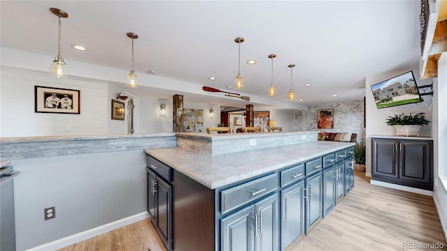 kitchen with light stone counters, light hardwood / wood-style floors, and hanging light fixtures