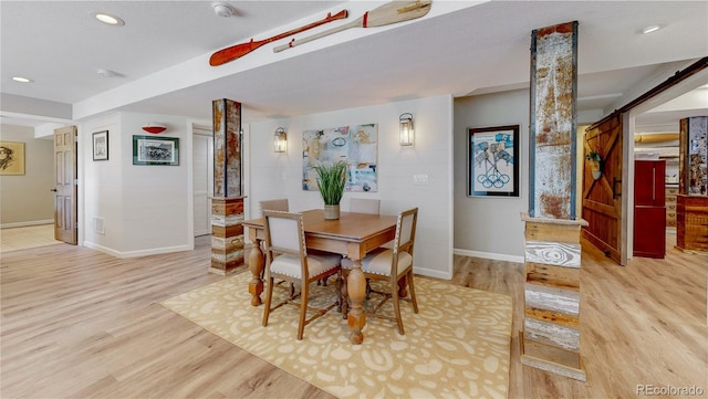 dining area featuring light hardwood / wood-style floors and decorative columns