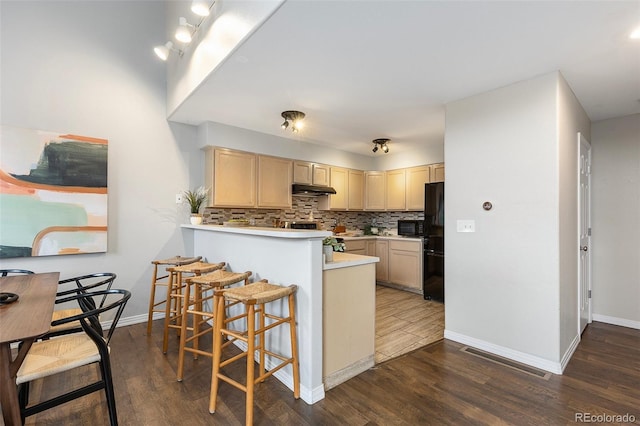 6450 W 44th Pl Unit B3, Wheat Ridge, CO 80033 - kitchen with black appliances, under cabinet range hood, dark wood-type flooring, a peninsula, and baseboards