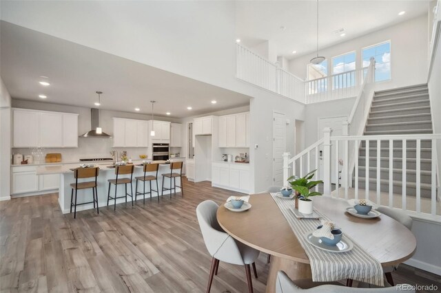 dining space with a towering ceiling and light hardwood / wood-style floors