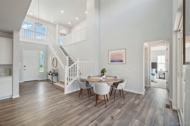 dining room with light hardwood / wood-style flooring and a high ceiling