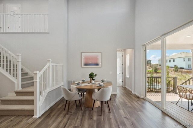 dining space featuring a high ceiling and hardwood / wood-style flooring