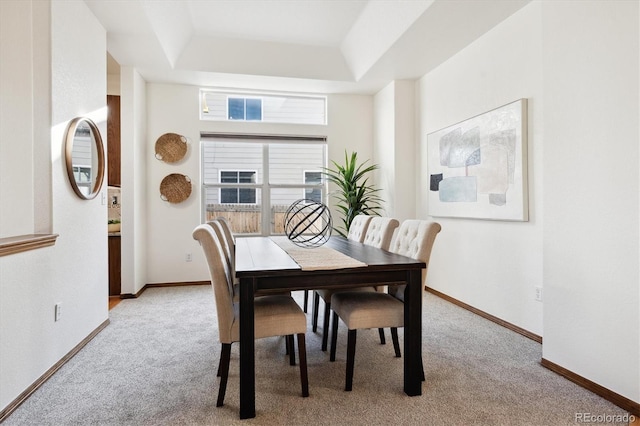 carpeted dining space featuring a raised ceiling