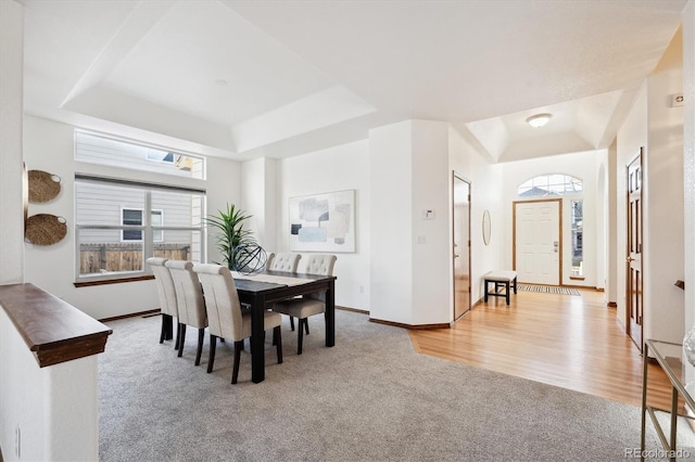 carpeted dining space featuring a raised ceiling