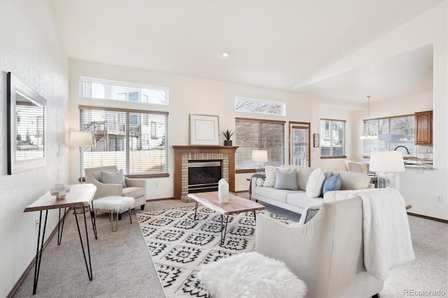 carpeted living room with vaulted ceiling, sink, and a brick fireplace