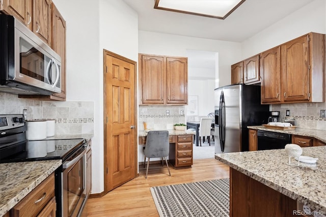 11144 Navajo St, Northglenn, CO 80234 - kitchen with appliances with stainless steel finishes, decorative backsplash, light stone counters, light wood finished floors, and brown cabinetry