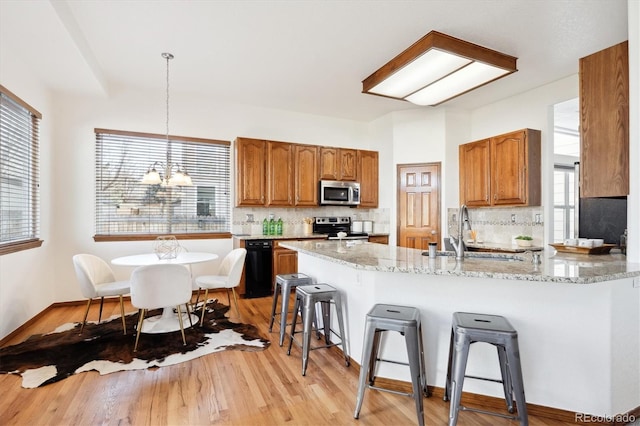 11144 Navajo St, Northglenn, CO 80234 - kitchen with appliances with stainless steel finishes, a breakfast bar, brown cabinets, and backsplash