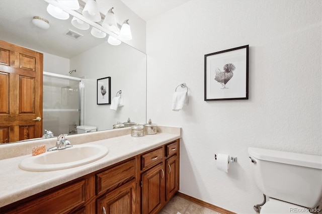 bathroom featuring tile patterned flooring, toilet, vanity, and walk in shower