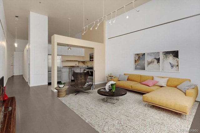 living area featuring a towering ceiling and track lighting