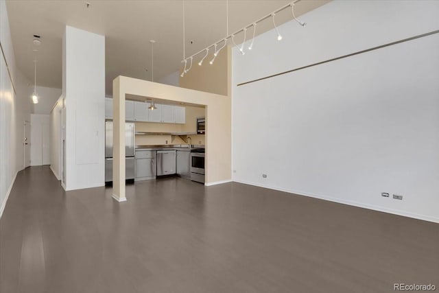 unfurnished living room with a towering ceiling, baseboards, and a sink