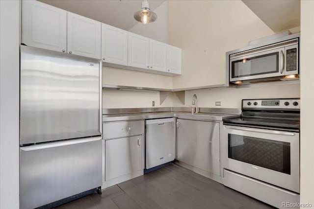 kitchen with white cabinets, stainless steel countertops, appliances with stainless steel finishes, dark wood-type flooring, and a sink