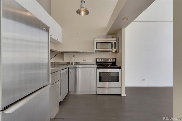 kitchen featuring dark wood-style floors, stainless steel appliances, stainless steel counters, white cabinets, and baseboards