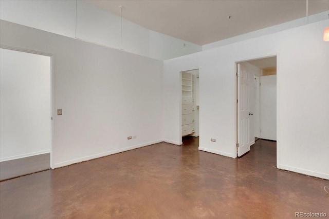 unfurnished room with finished concrete flooring and baseboards