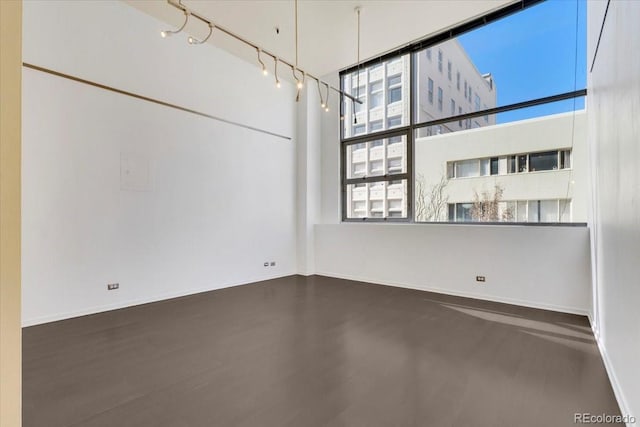 empty room featuring rail lighting and baseboards