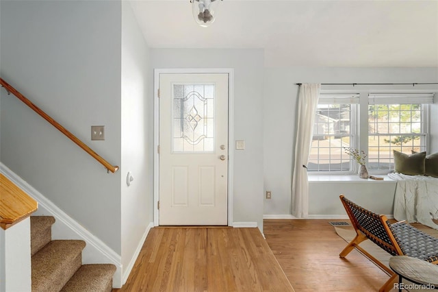 foyer entrance with visible vents, stairway, baseboards, and light wood-type flooring