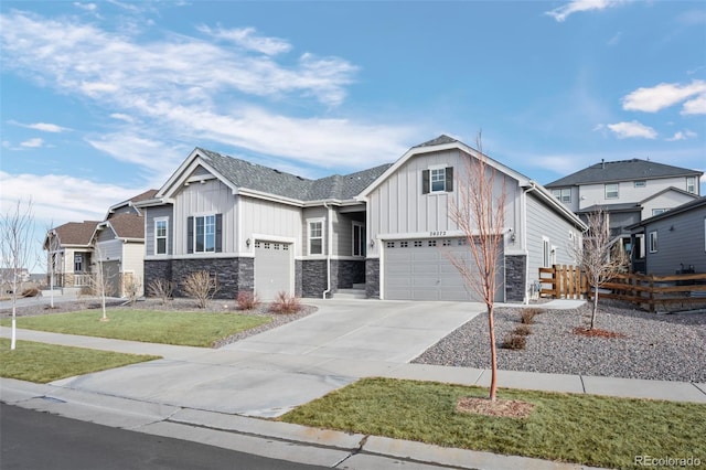 view of front of house with driveway, an attached garage, fence, a front lawn, and board and batten siding