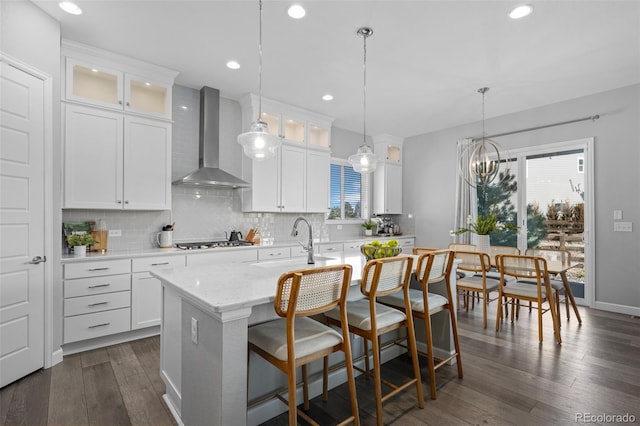 kitchen with stainless steel gas cooktop, wall chimney range hood, a sink, and tasteful backsplash