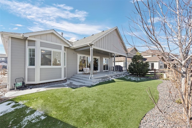 rear view of house with ceiling fan, fence, a yard, board and batten siding, and a patio area