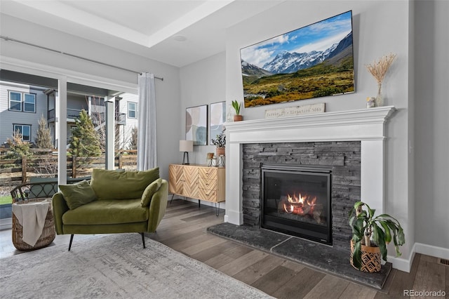 living area featuring a fireplace, baseboards, and wood finished floors