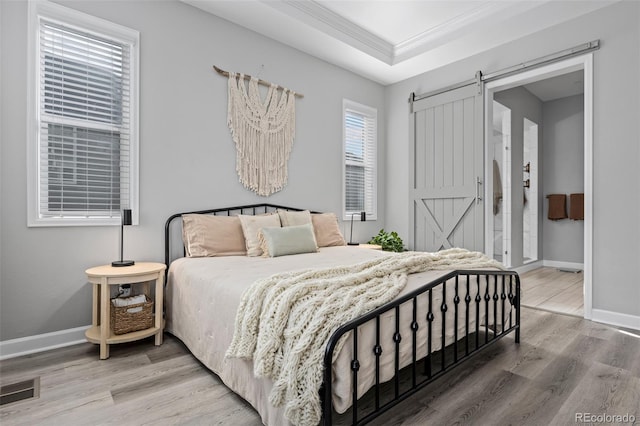 bedroom with ornamental molding, a barn door, wood finished floors, and baseboards