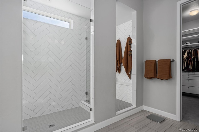 bathroom with a shower stall, baseboards, and a spacious closet