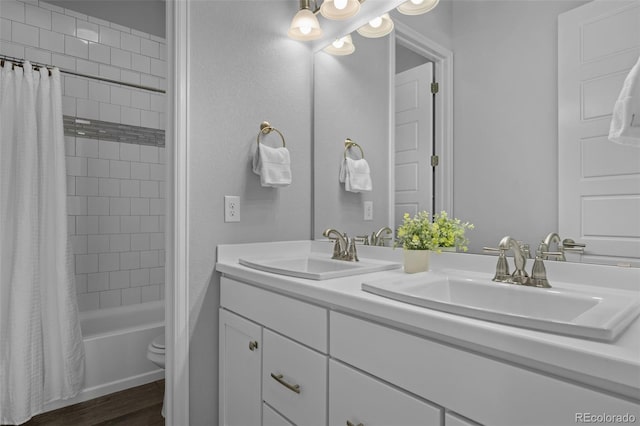 bathroom with shower / bath combination with curtain, double vanity, a sink, and wood finished floors