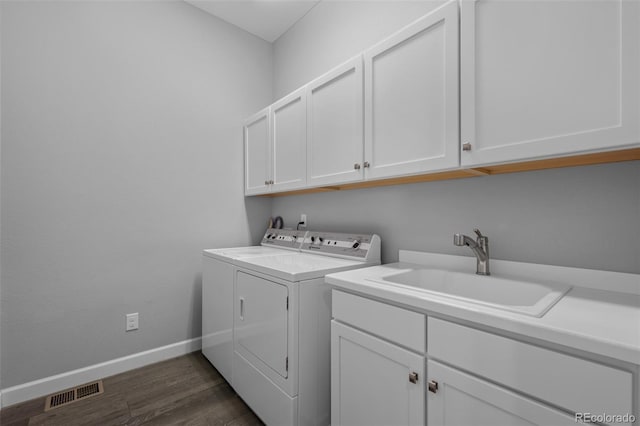 laundry area with cabinet space, visible vents, washing machine and dryer, a sink, and baseboards