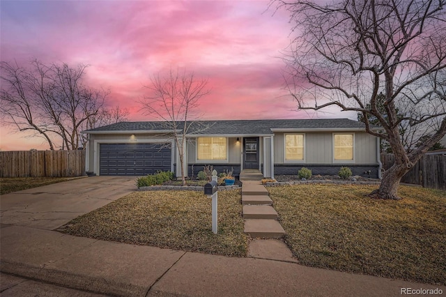 single story home with concrete driveway, an attached garage, and fence