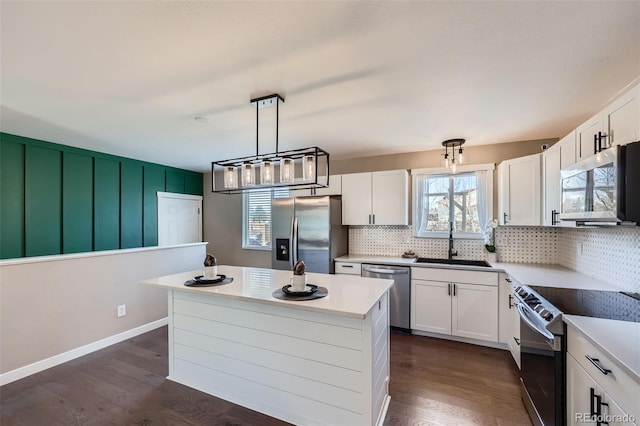 kitchen with dark wood-type flooring, a sink, white cabinetry, stainless steel appliances, and decorative backsplash