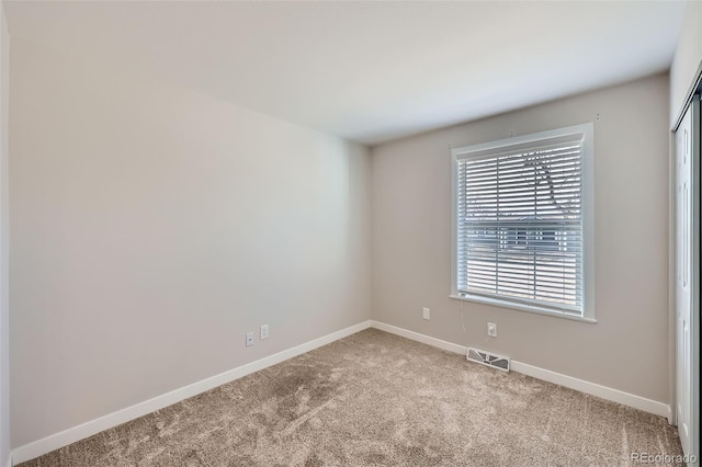 carpeted empty room with visible vents and baseboards