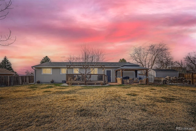 rear view of property featuring a gazebo, a yard, and fence