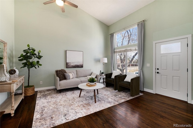 living area featuring dark wood-style floors, ceiling fan, high vaulted ceiling, and baseboards