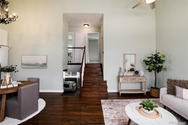 living room with stairway, ceiling fan with notable chandelier, baseboards, and wood finished floors