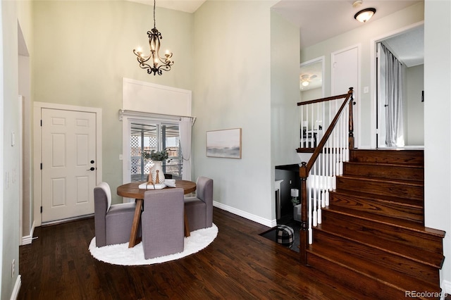 dining area with baseboards, stairs, a towering ceiling, wood finished floors, and a notable chandelier